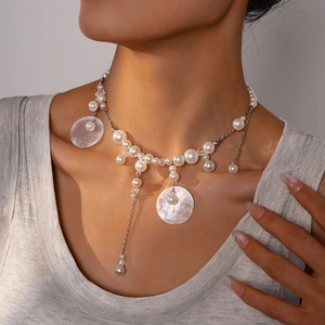 Close-up of pearl necklace with shell pendant on woman's neckline for beach vacation style