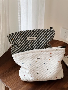Macro shot of two woven cosmetic bags with stripes and dots on a wooden table surface
