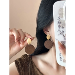 Detail view of vintage wooden round pendant earrings with matte gold oval metal studs