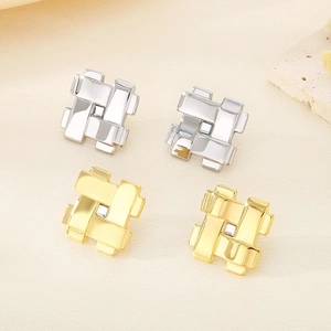 Vue macro des boucles d'oreilles tissées géométriques avec cristal en or et argent