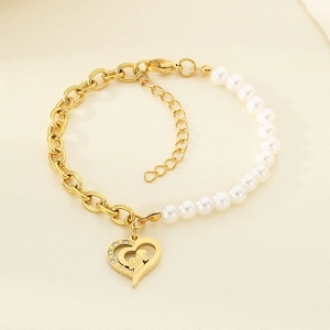 Detail of heart pendant with mother and child cutout on gold and pearl bead bracelet
