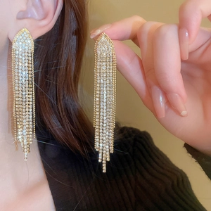 Macro detail of elegant golden tassel leaf earrings with sparkling rhinestones on model