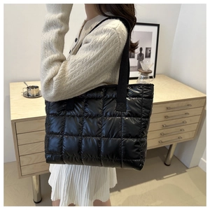 Model wearing a large black puffer quilted crossbody bag with a lattice pattern design