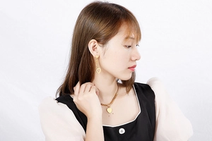 Model wearing a polished golden stainless steel heart earring and necklace jewelry set