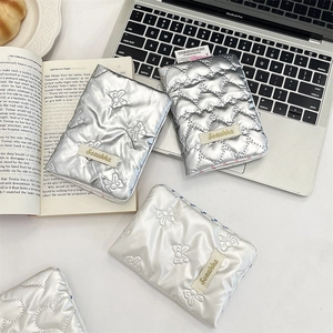 Detailed view of quilted bow-patterned laptop sleeve in silver and pearl white