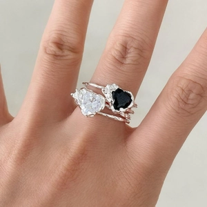 Close-up of S925 silver rings with heart-shaped white and black zircons and lava texture