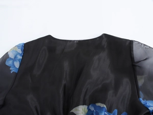 Dettaglio dell'abito in organza nera con stampa floreale blu e cuciture in rete