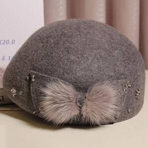 Detail of grey wool beret featuring a mink fur bow and sparkling rhinestone accents