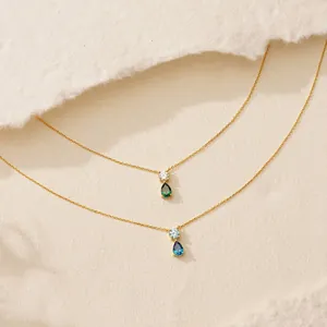 Detail view of 18K gold plated necklaces with teardrop emerald and blue zircon pendants