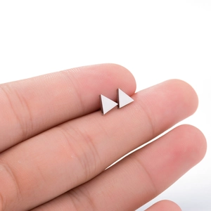 Macro shot of silver minimalist triangle stud earrings held to show accurate size scale