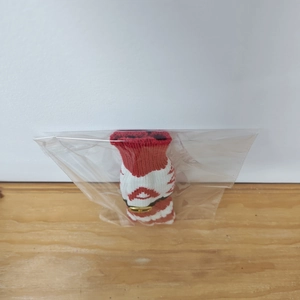 Red and white knitted wine bottle cover with a golden D-buckle, perfect for holiday decor.