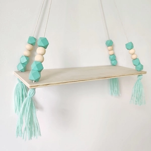 Detail of mint green tassel and geometric wood beads on a hanging wall shelf