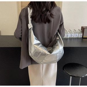 Detail of silver half-moon shoulder bag with pleated texture and stylish knotted strap