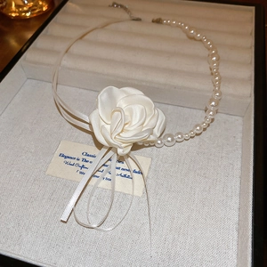 Détail d'un collier de fleurs en tissu et perles présenté dans un écrin à bijoux haut de gamme