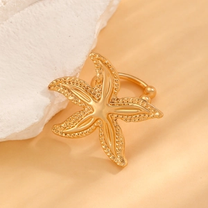 Close-up of gold starfish ear cuff with textured finish on a white natural stone