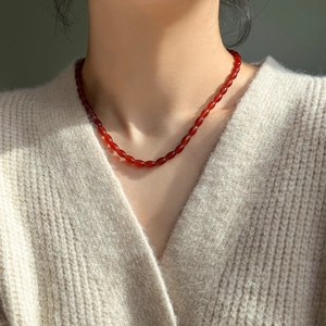 Detail of red agate beaded necklace on model, showing small oval beads and elegant texture