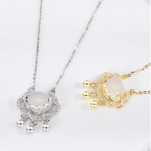 Detail of silver and gold ruyi lock necklaces with white chalcedony and bells
