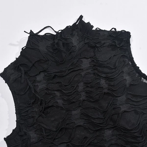 Close-up of distressed ripped texture and shredded fringe detail on black knit dress