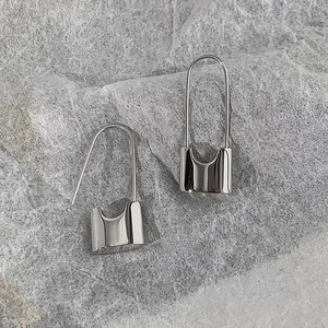 Macro shot of silver minimalist U-shaped padlock earrings on grey stone texture