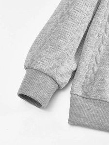 Close-up of grey sweatshirt showing diamond quilted texture and ribbed cuffs
