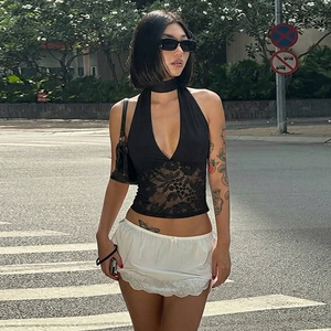 Detail of black lace patchwork halter top and white lace mini skirt on a model