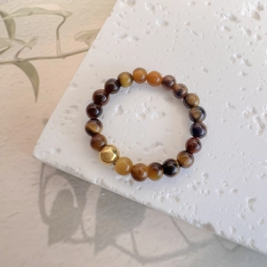 Close-up of tiger eye stone beaded ring with a polished gold stainless steel bead