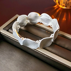 Macro view of matte silver link bracelet with minimalist curved metal pieces in a jewelry box