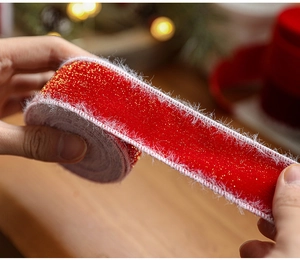 Close-up of red velvet Christmas ribbon with gold glitter and white fuzzy edge detail