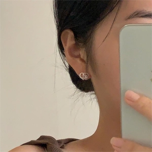Close-up of elegant silver CD letter interlocking stud earrings worn by a female model
