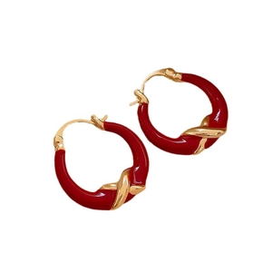 Minimalist red hoop earrings with golden cross pattern on a white background