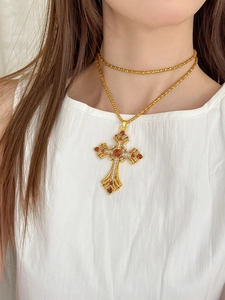 Gros plan du collier croix vintage avec pierres ambrées et diamants sur un modèle