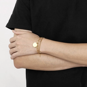Detail of layered gold stainless steel bracelet featuring round pendant and link chains