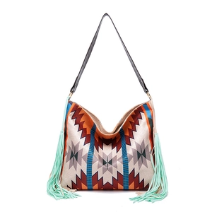 Detail of bohemian geometric woven hobo bag with colorful patterns and long green tassels