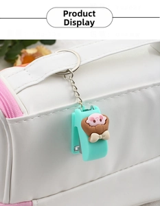 Mini-Hefter-Schlüsselanhänger in Mintgrün mit Cartoon-Figur an weißer Ledertasche hängend