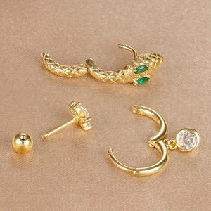 Detailed macro view of gold snake ear cuff and star studs on brown silk fabric