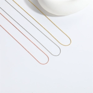 Detailed view of three minimalist metal chains in gold, silver, and rose gold finishes
