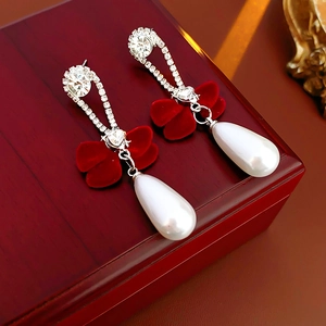 Close-up of velvet bow earrings with white pearl drops on a red vintage wooden box