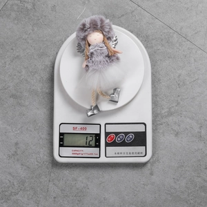 Christmas angel doll decoration with mesh skirt being weighed on a digital scale showing 12g