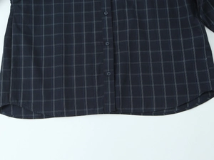 Detailed view of the plaid poplin shirt hem featuring dark blue check pattern and stitching
