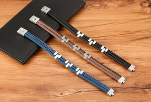 Close-up of triple-layered leather bracelets in blue, brown, and black with steel clasp