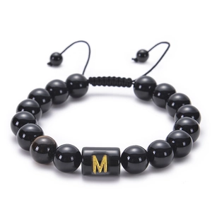 Detailed view of adjustable black obsidian bead bracelet with golden letter M charm