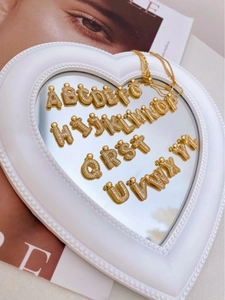 Macro shot of 26 gold letter pendants with rhinestones on a heart mirror