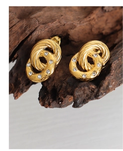 Close-up of gold double loop earrings with zircon inlays on rustic wood background