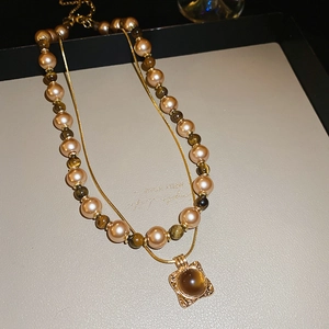 Detail of vintage layered necklace featuring tiger eye beads and square stone pendant