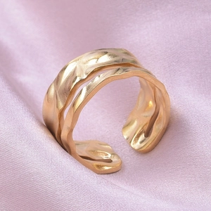 Macro detail of golden stainless steel ring with hammered texture on purple silk