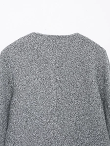 Detail of grey bouclé texture and collar on fashion jacket with golden button trim
