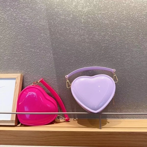Detail of heart-shaped mini bags in magenta and purple with shiny finish and gold hardware