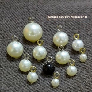 Macro detail of various ABS pearl pendants with gold and silver metal rings for DIY jewelry