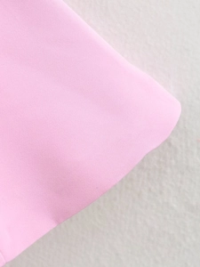Gros plan sur la texture du tissu rose et les coutures du haut cintré à nœud