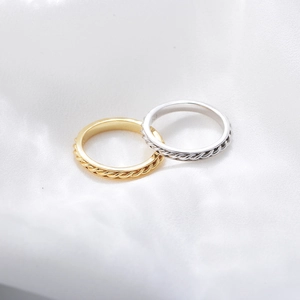 Macro shot of gold and silver twisted rings with 925 silver engraving on white silk